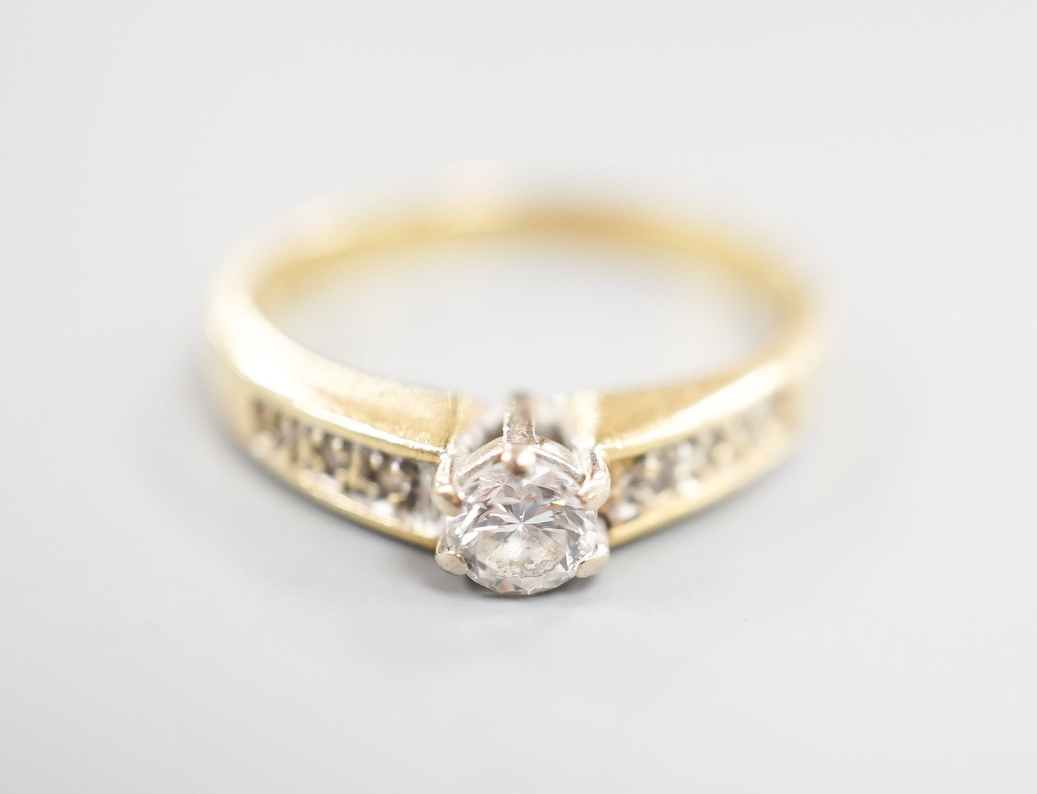 A modern 18ct gold and single stone diamond ring, with diamond set shoulders, size L, gross 2.4 grams.